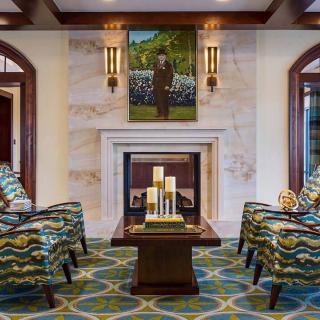 A luxurious living room with a central fireplace, surrounded by patterned chairs and elegant decor.