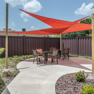 A patio area with a red shade sail and outdoor furniture.