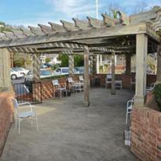 A pergola with outdoor seating on a patio surrounded by a brick wall.