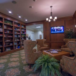 A cozy library with comfortable seating, bookshelves, and a television.