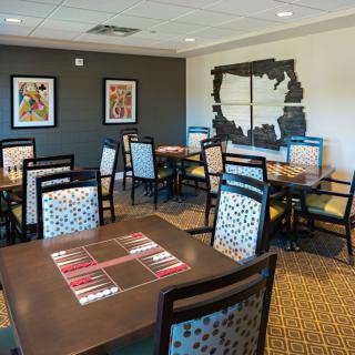 A modern dining area featuring elegantly arranged tables and chairs, with decorative artwork on the walls.