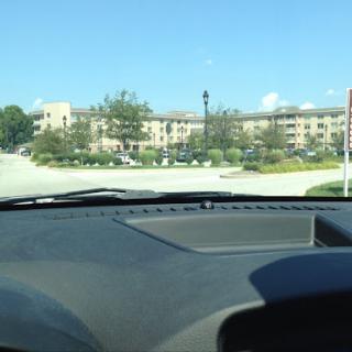 A view from inside a car, looking towards a building with a clear blue sky.