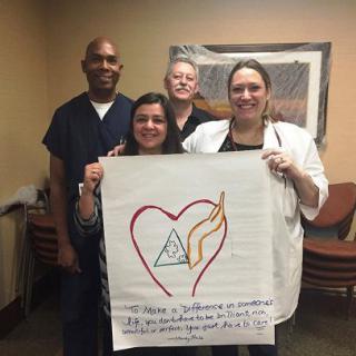 A group of healthcare professionals holding a poster with a heart design and text.