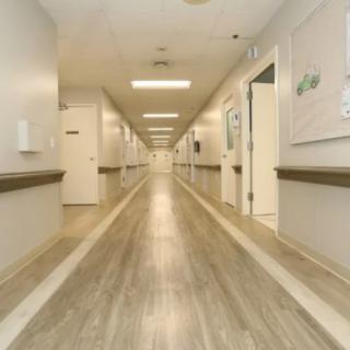 An empty hallway in a hospital with bright lighting and clean floors.