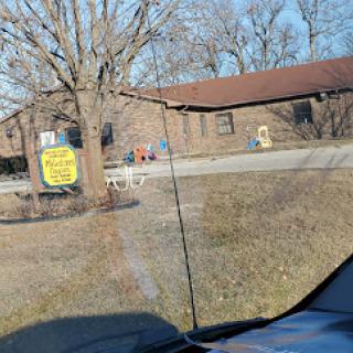 A view of a brick building with a tree in the foreground and a visible sign.