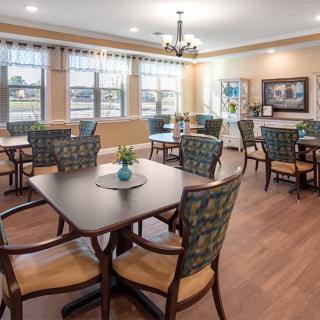 A well-lit dining area with arranged tables and chairs, featuring elegant decor.