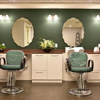 A stylish barbershop interior with two chairs, mirrors, and elegant lighting.