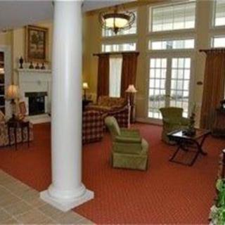 A spacious living room with a fireplace, armchairs, and large windows.