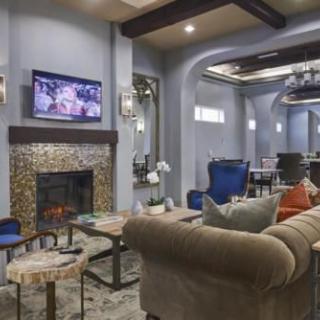 A modern living room with a cozy fireplace, plush sofas, and a television mounted above.