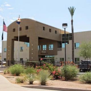 A modern building with a distinctive architectural design, surrounded by desert landscaping and palm trees.