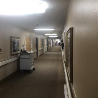 A quiet hospital hallway with equipment and framed art on the walls.