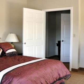 A cozy bedroom with a neatly made bed and an open door leading to another room.