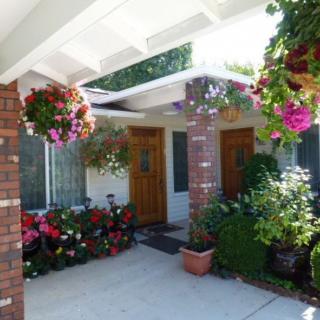 A welcoming house entrance adorned with colorful hanging flower baskets and potted plants.