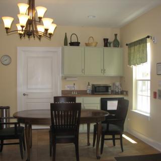 A cozy dining area with a wooden table, chairs, and cabinets under warm lighting.