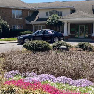 A parked car in front of a building, surrounded by a colorful flowerbed.