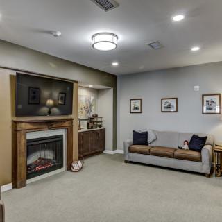 A cozy living room featuring a fireplace, television, and comfortable sofa with wall art decor.