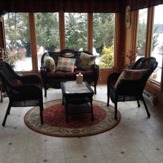 A cozy sunroom with wicker furniture, offering a scenic view of the outdoors.