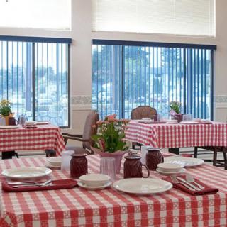 A cozy dining area with tables covered in red and white checkered tablecloths, set for a meal.