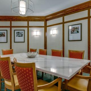 A modern conference room featuring a large meeting table and comfortable chairs, with framed artwork on the walls.