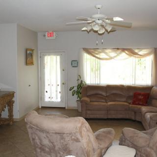 A cozy living room with comfortable seating and a ceiling fan.