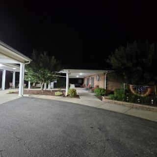 A quiet night view of a well-lit building with surrounding greenery.