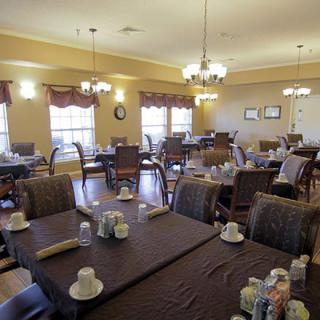 A spacious dining room with neatly arranged tables and chairs, illuminated by elegant chandeliers.