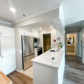 A modern kitchen with white cabinets, stainless steel appliances, and bright lighting.