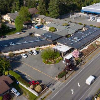 Aerial view of a building complex with a parking lot and surrounding trees.