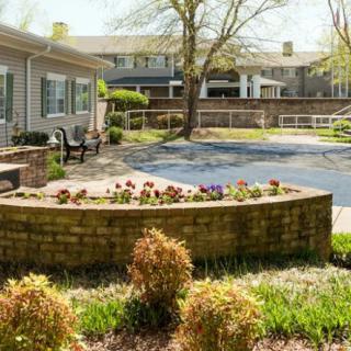 A serene outdoor garden area featuring a raised flower bed and a bench, perfect for relaxation.