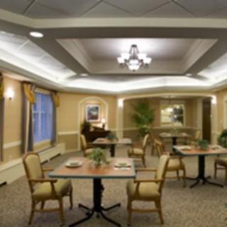 An elegant dining area with tables and chairs, featuring decorative ceiling lights and large windows.
