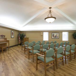An interior view of a meeting room with arranged chairs, a lectern, and decorative wall art.