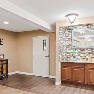 A modern interior room with wooden flooring, featuring a decorative wall and built-in cabinet.