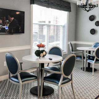 A modern dining area with round tables and chairs, featuring a television, window, and decorative elements.
