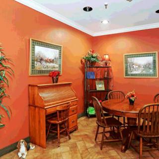 A cozy dining room with a round wooden table, matching chairs, a bookshelf, and framed artwork on the walls.