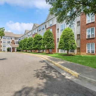 A modern apartment complex surrounded by well-maintained landscaping and blue skies.