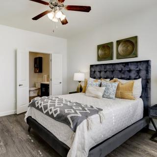 A modern bedroom with a luxurious bed, stylish decor, and a ceiling fan.