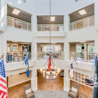 A modern atrium with a chandelier and flags, surrounded by balconies.