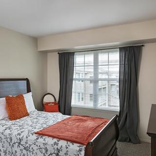 A cozy bedroom with a bed, window with curtains, and simple decor.