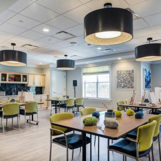 A modern dining area with contemporary lighting and furniture, featuring a kitchen in the background.