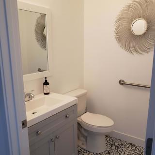 A minimalist bathroom with a sink, toilet, and decorative mirror.