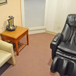 A cozy waiting room featuring a massage chair and a small table with refreshments.