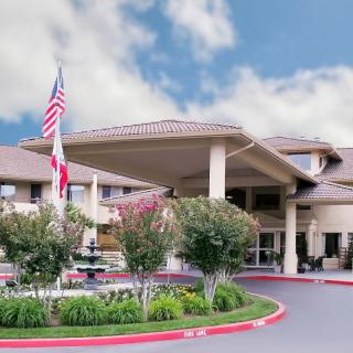 A large building entrance with flags, a fountain, and landscaped surroundings.
