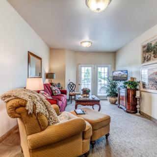 A cozy living room with comfortable seating and a television, filled with natural light.