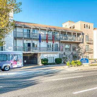 A street view of a hotel building with a bus parked in front.