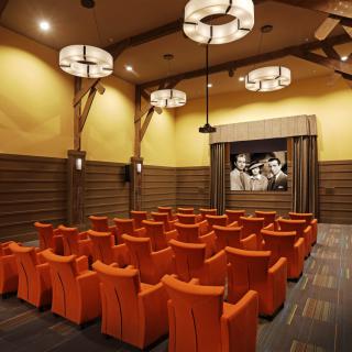 A cozy theater room with orange seating and a classic film on the screen.