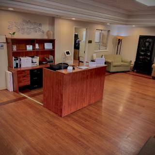 A well-lit and inviting reception area with a wooden front desk and comfortable seating.