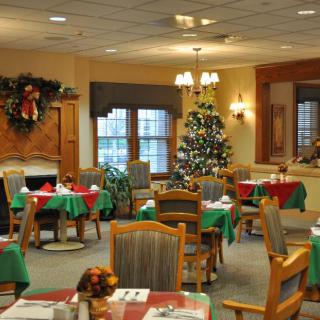 A festive dining room decorated for the holidays, featuring a Christmas tree and colorful table settings.