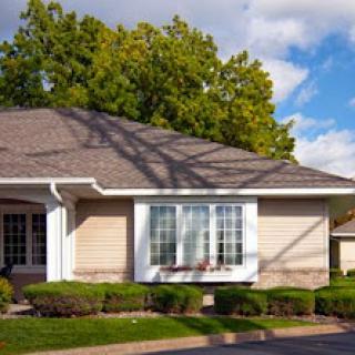 A charming single-story house with well-maintained landscaping and a clear blue sky.