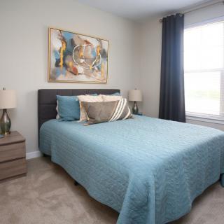 A modern bedroom with a double bed, artwork on the wall, and bedside lamps.