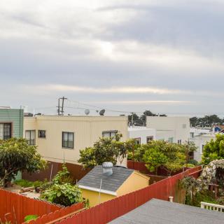 A view of a suburban neighborhood with houses, backyards, and a cloudy sky.